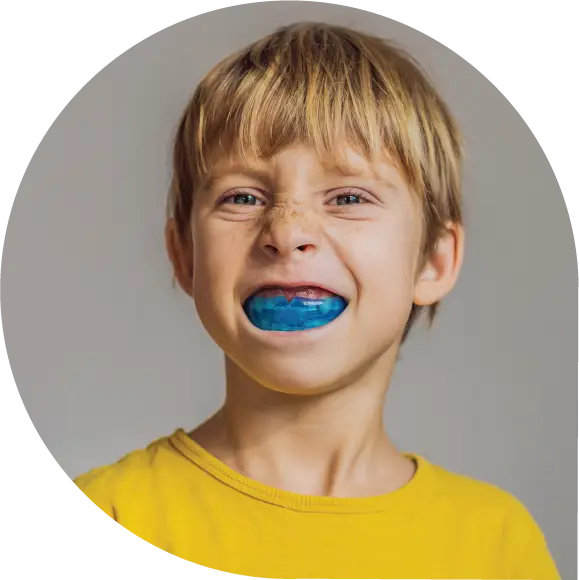 A child in a yellow outfit proudly displaying a Custom Tailored Sports Mouthguard.